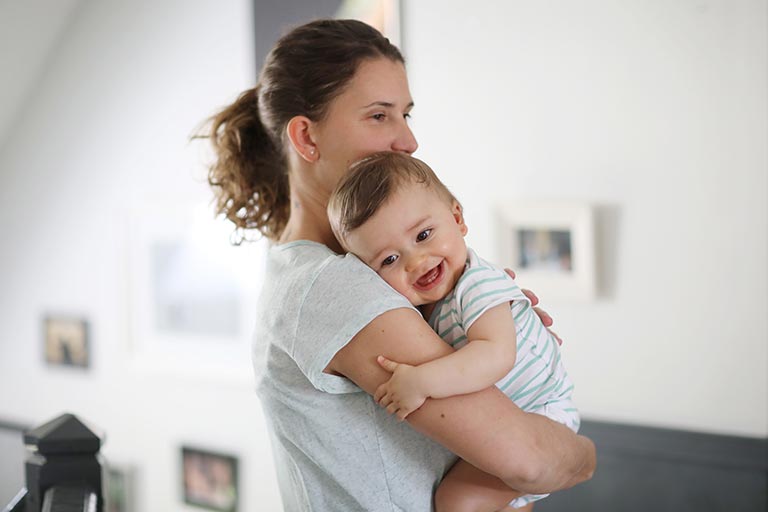 A 8 months old baby in the arms of his mum