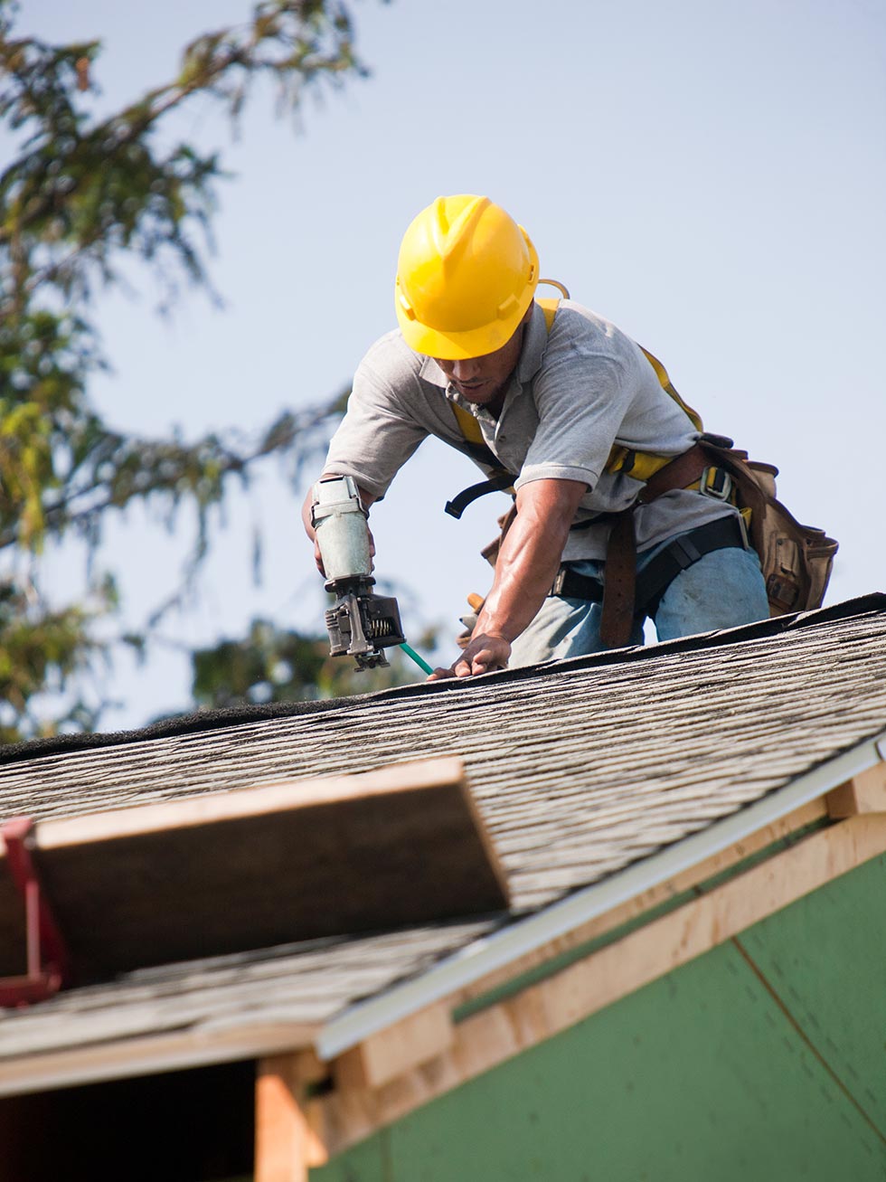 Roofer installing shingles on peak of roof